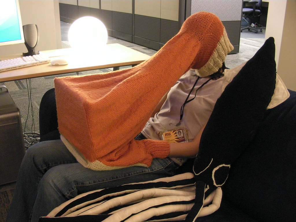 la tete dans un pull qui englobe aussi un ordinateur